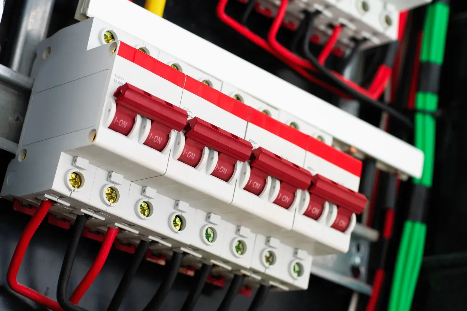 Electrical circuit breakers with red switches and wires.