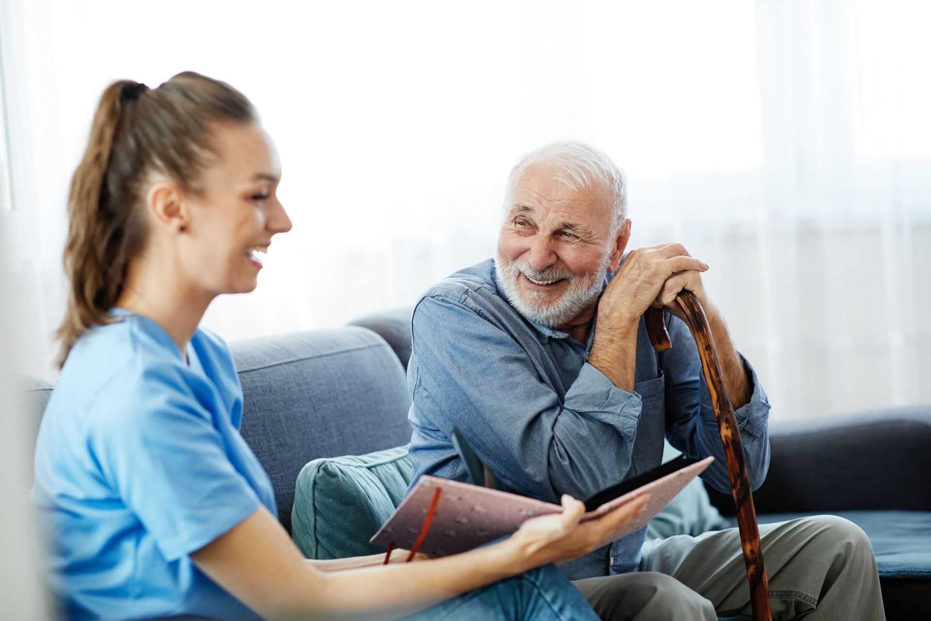 Caregiver and senior man looking at a file together on a sofa.