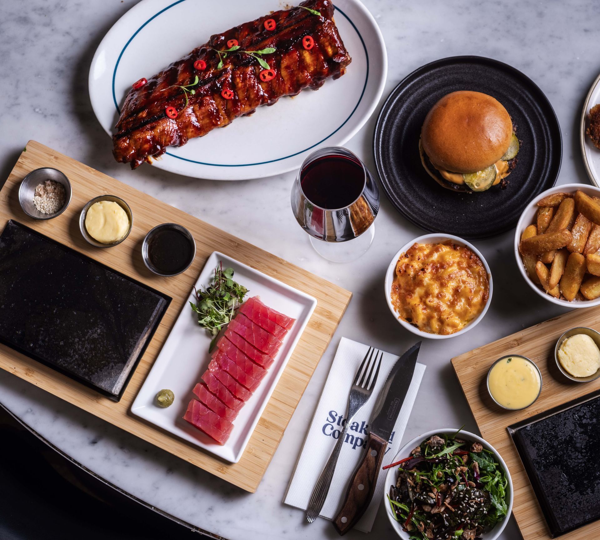 Steak and Company restaurant exterior. Green facade, large windows, outdoor seating, and a busy street scene.