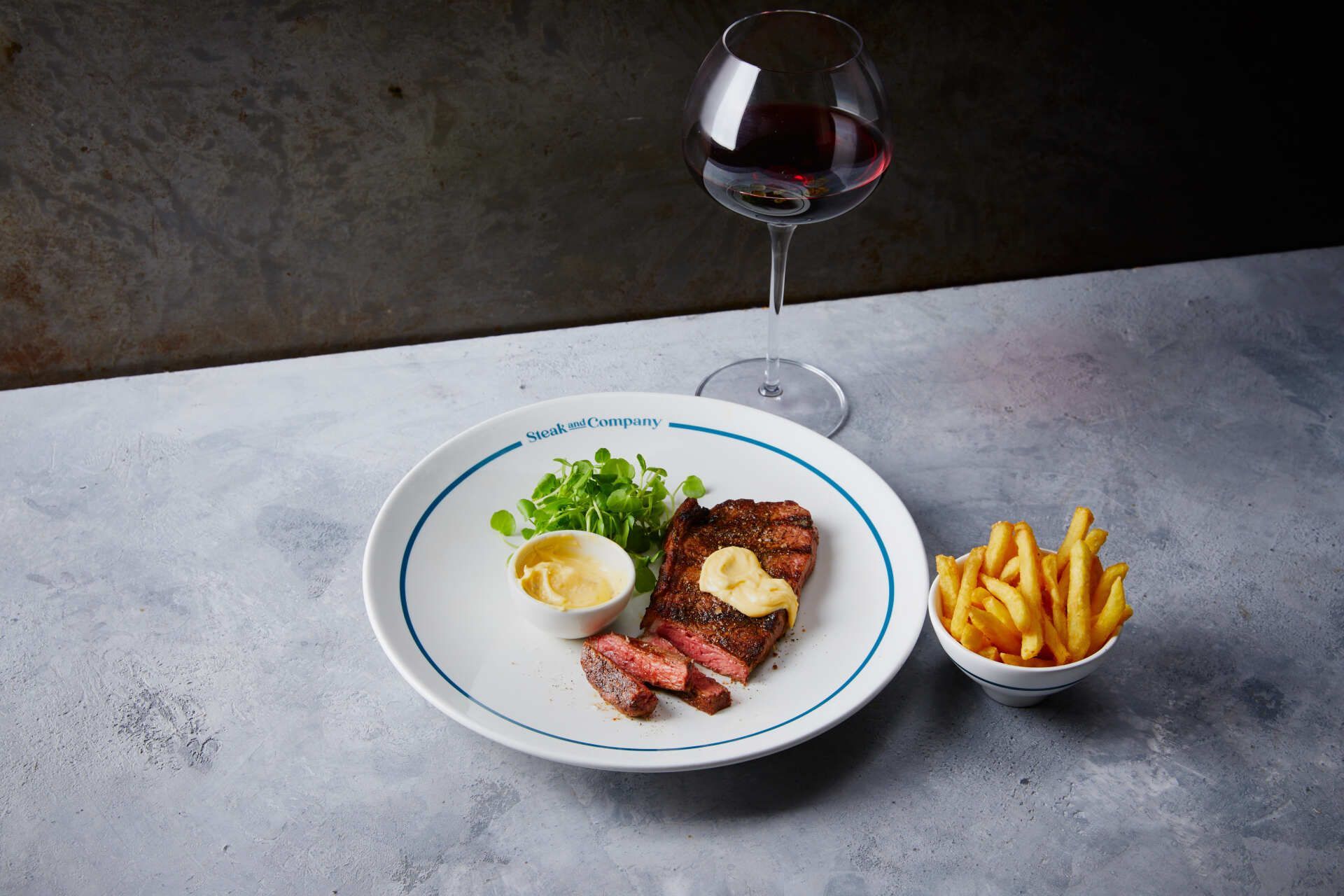 Steak dinner on a plate with peas, fries, and a glass of red wine.