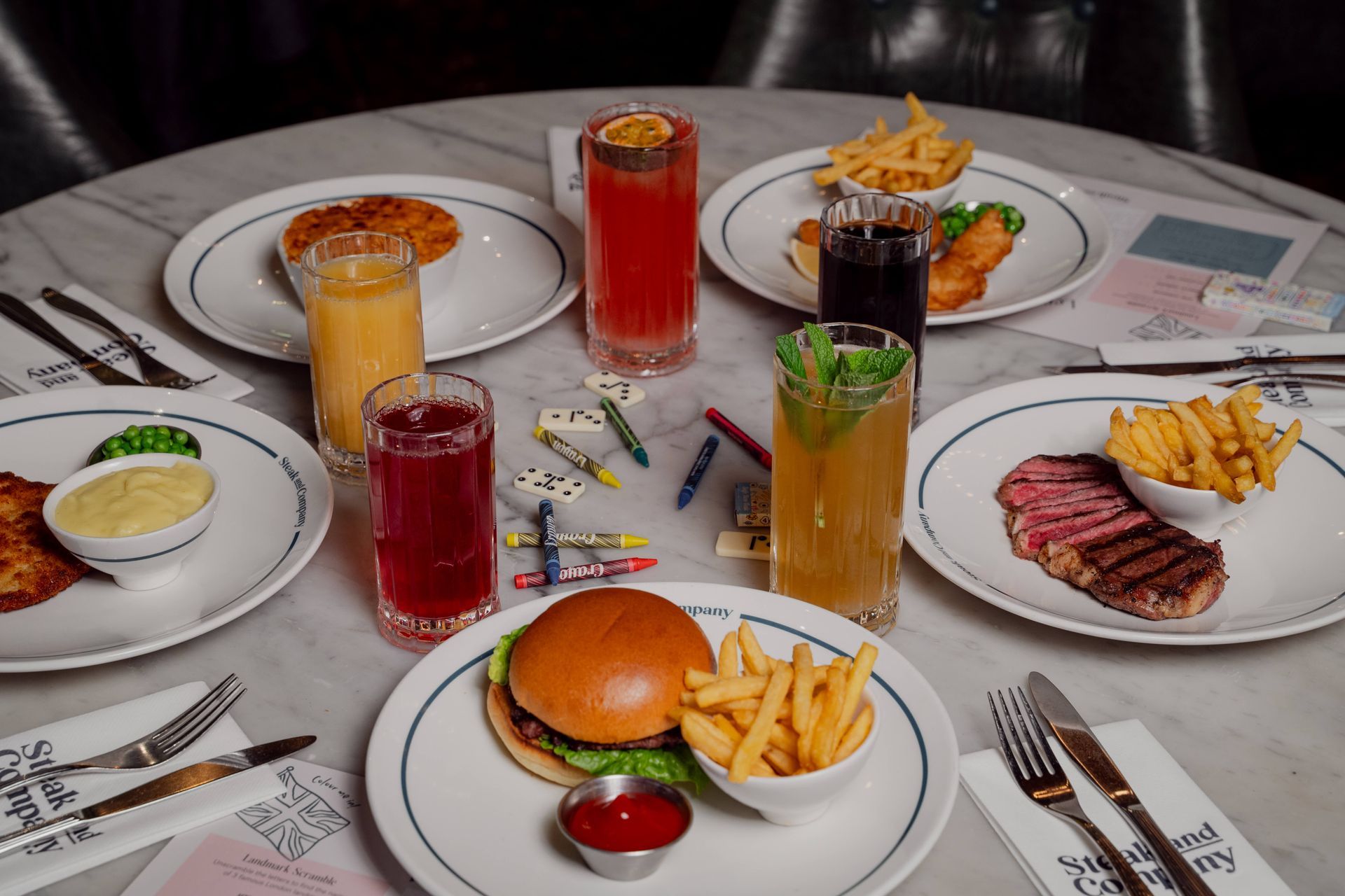 Steak and Company child's meal: steak, fries, ketchup, orange juice, toys, and crayons on a rustic table.