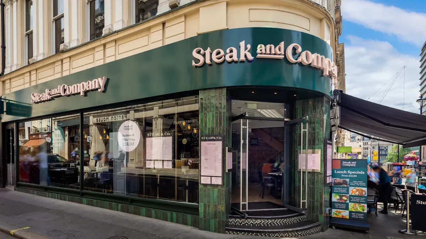 Steak and Company restaurant exterior with green and beige facade, corner entrance.