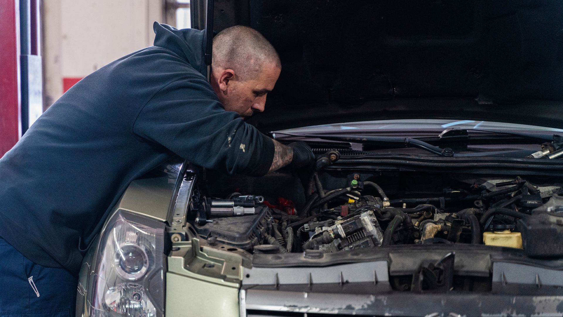 A mechanic working in the auto repair shop fixing a car. A mechanic working in the auto repair shop fixing a car.