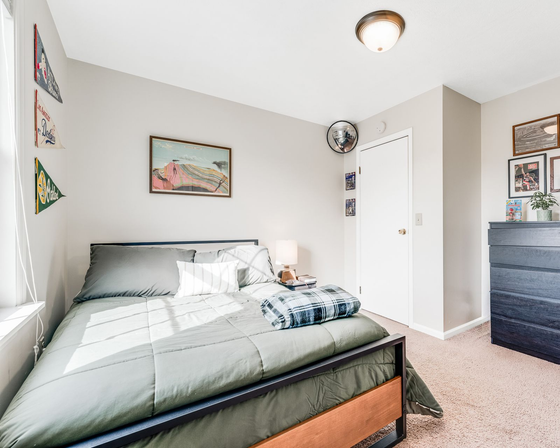 Bedroom with bed, dresser, art, and white door.