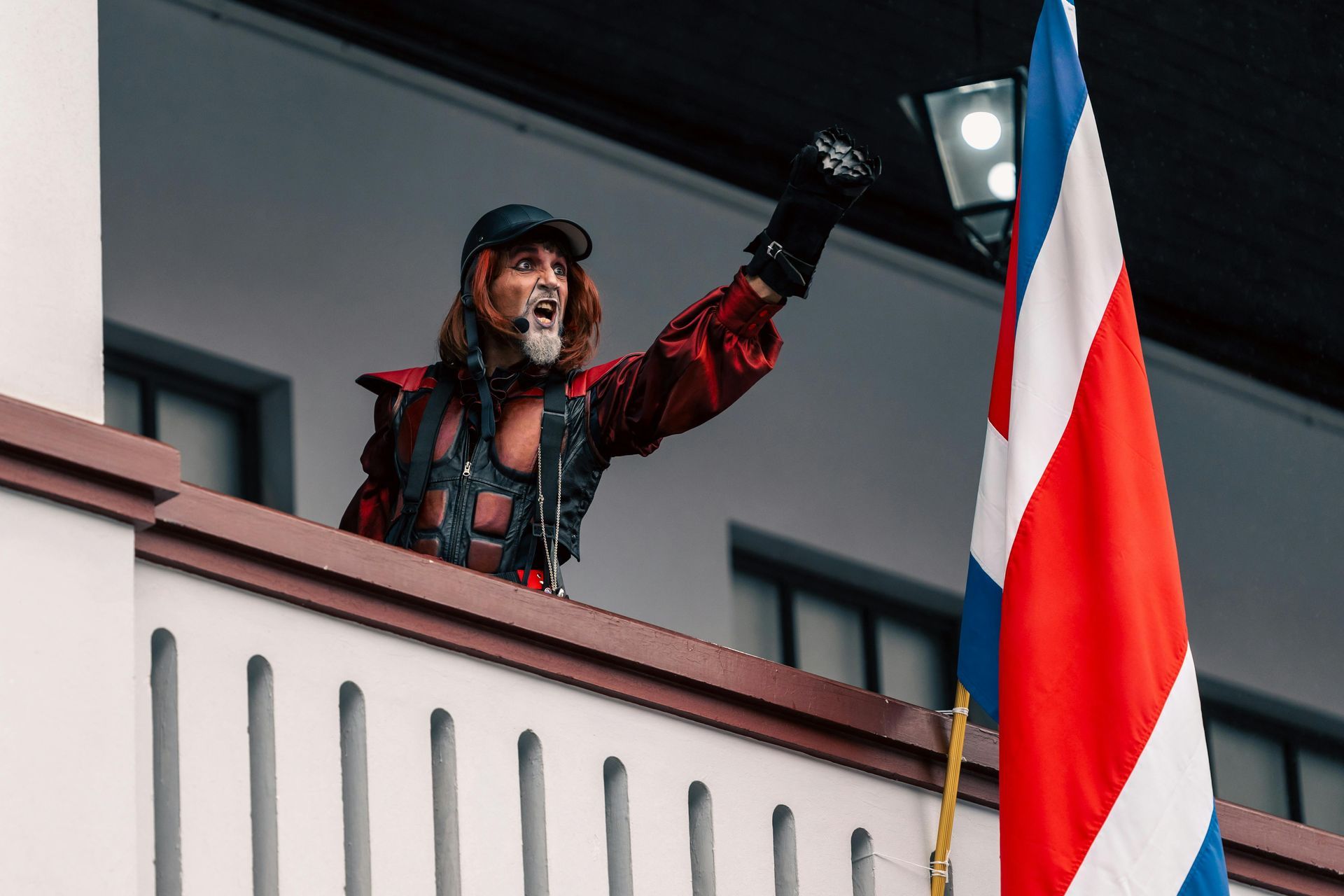 Un uomo è in piedi su un balcone con in mano una bandiera