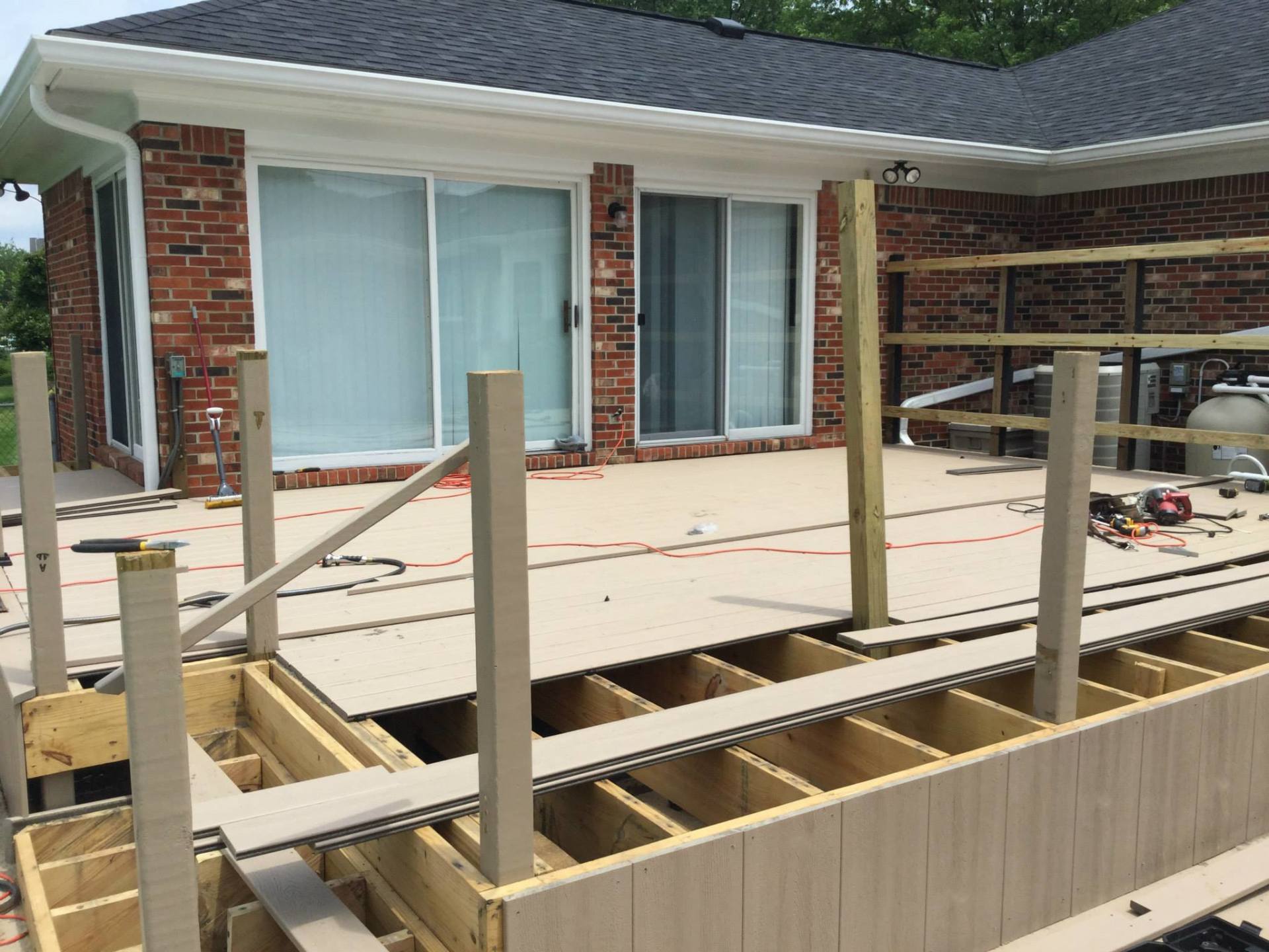A wooden deck is being built in front of a brick house.