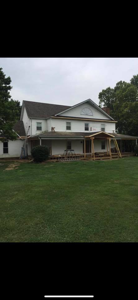 A large white house with a porch and a large lawn in front of it.
