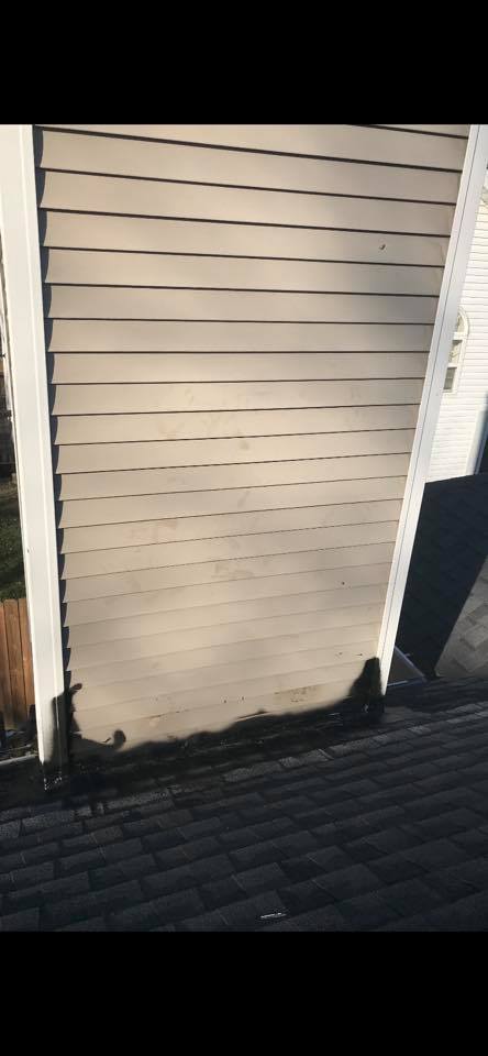 A white siding on a house with a black roof.