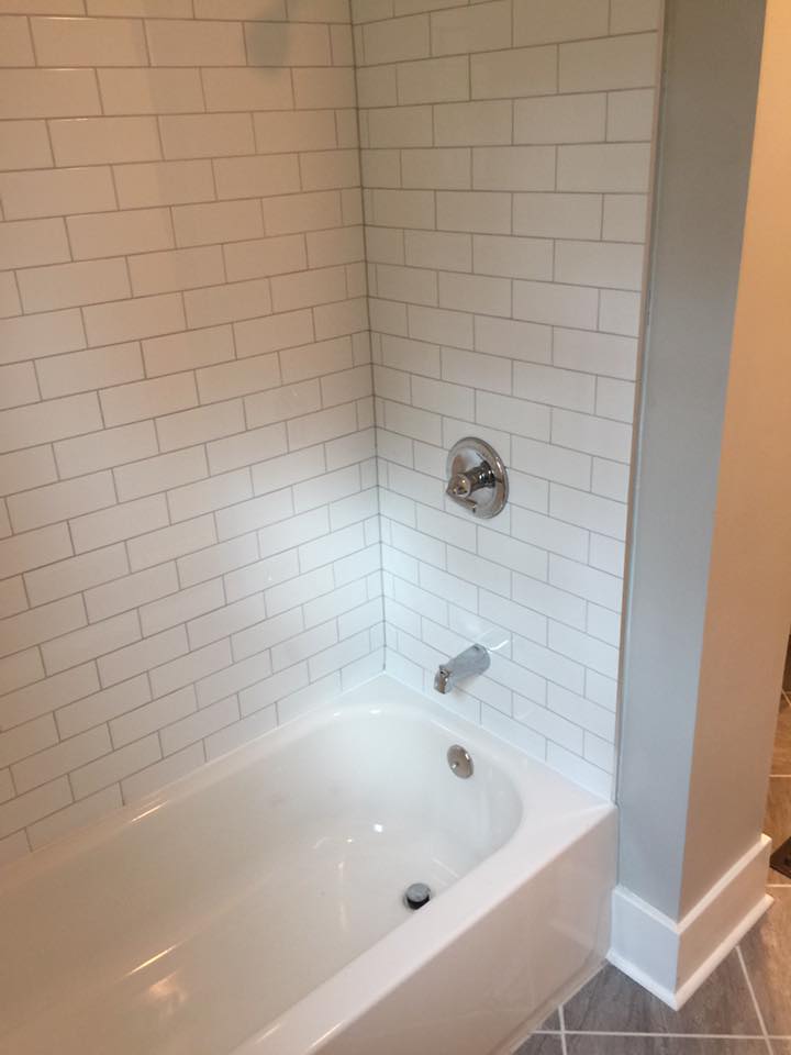 A bathtub in a bathroom with white subway tile walls.