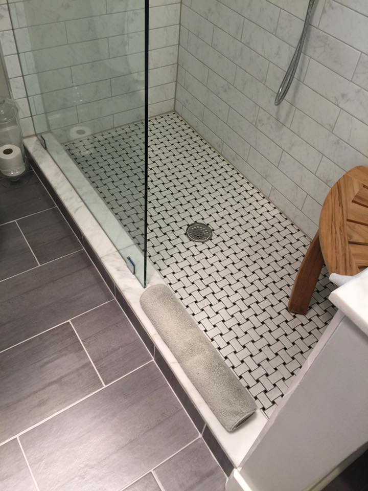 A bathroom with a walk in shower and a towel on the floor.