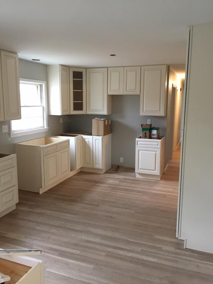 A kitchen with white cabinets and wooden floors is being remodeled.