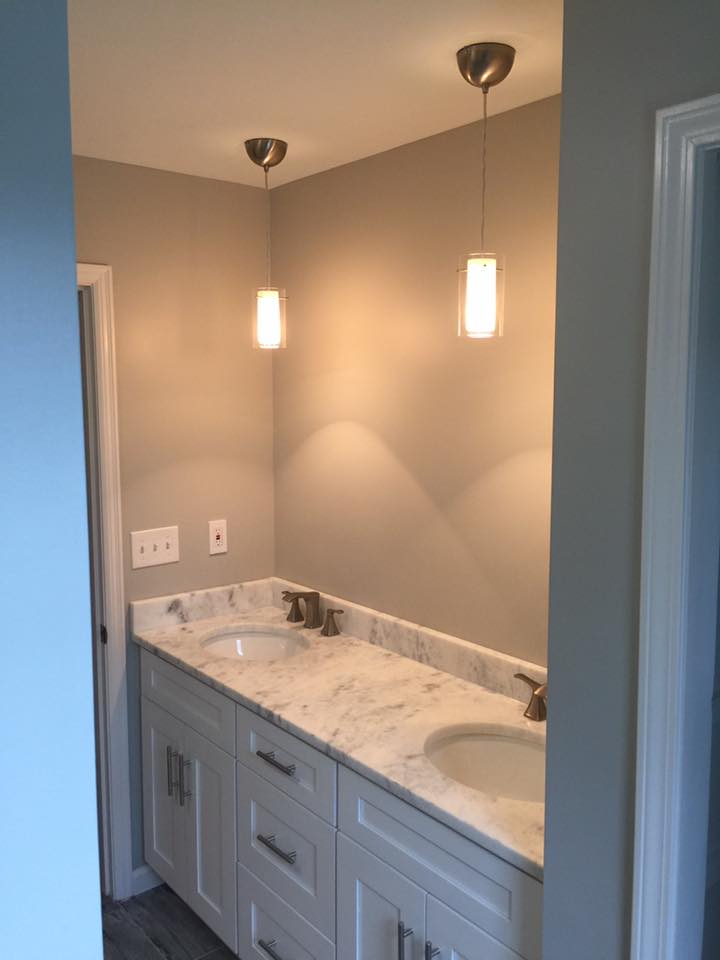 A bathroom with two sinks and a marble counter top.