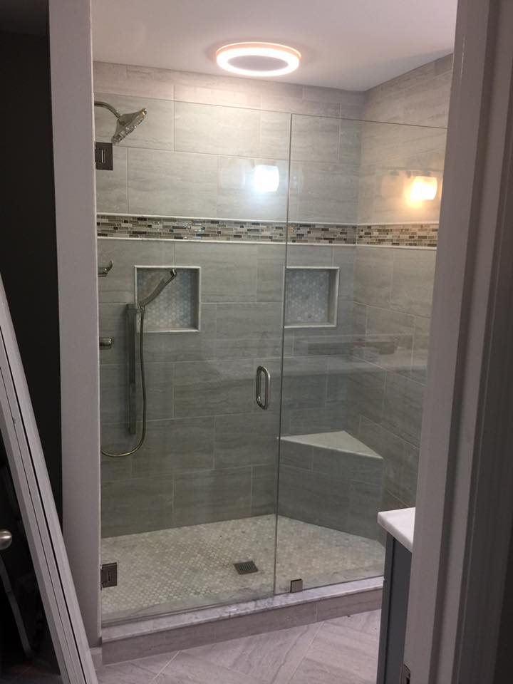 A bathroom with a walk in shower with a glass door.