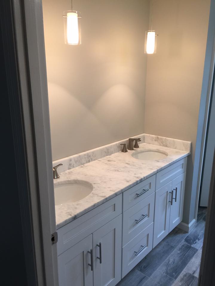A bathroom with two sinks and a marble counter top.