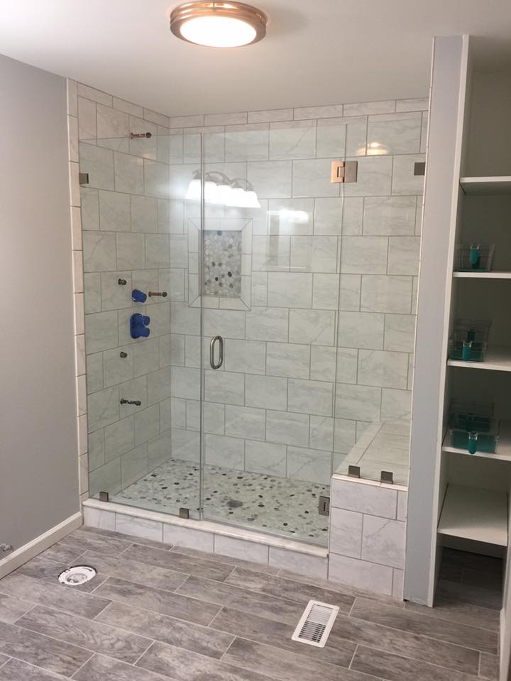 A bathroom with a walk in shower with a glass door.