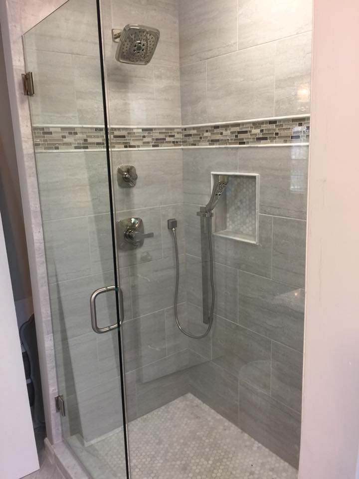 A bathroom with a walk in shower with a glass door.