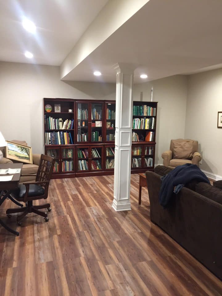 A living room with a couch , chair , desk and bookshelves.