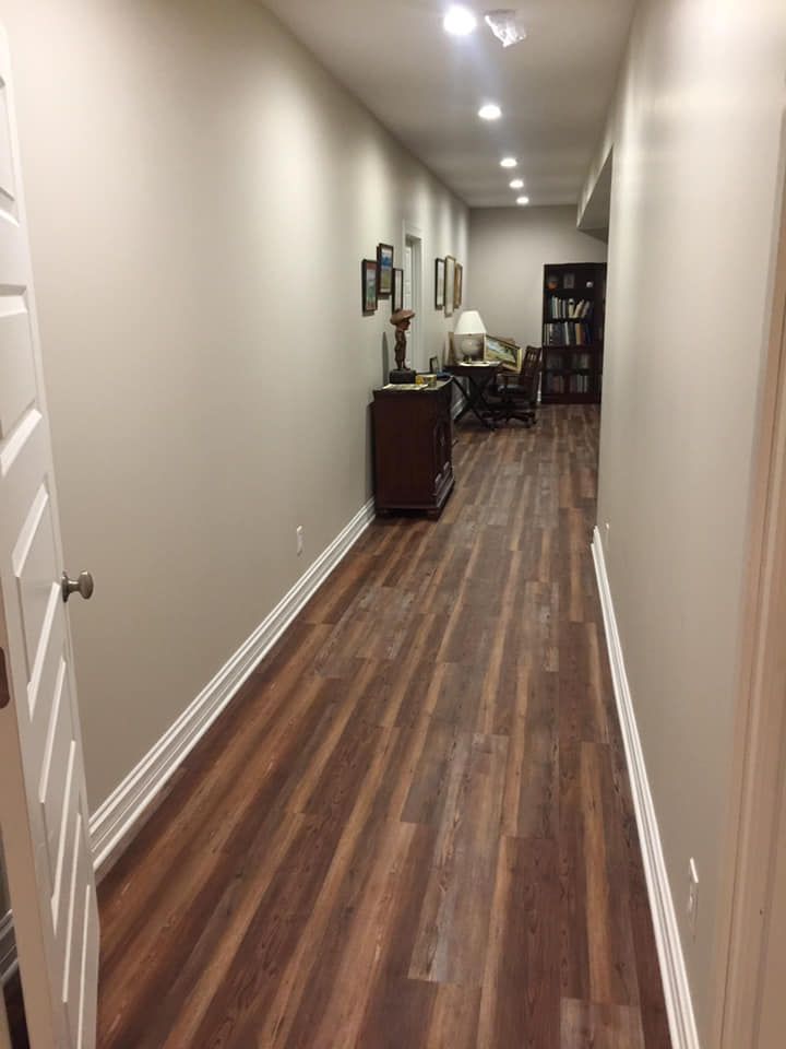 A long hallway with hardwood floors leading to a living room.