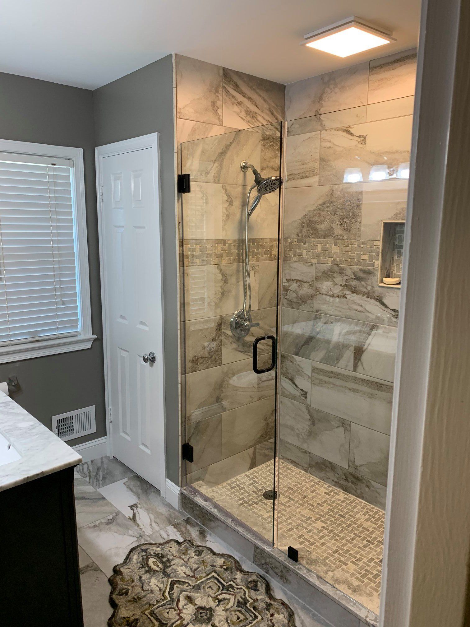A bathroom with a walk in shower with a glass door.