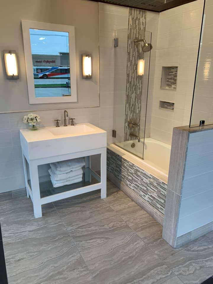 A bathroom with a sink , tub and mirror.