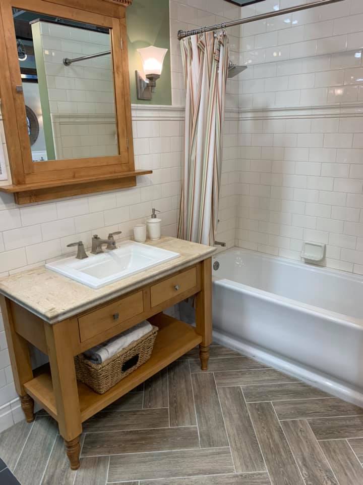 A bathroom with a sink , mirror , tub and shower.