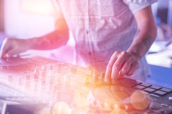 A dj is playing music on a mixer at a party.