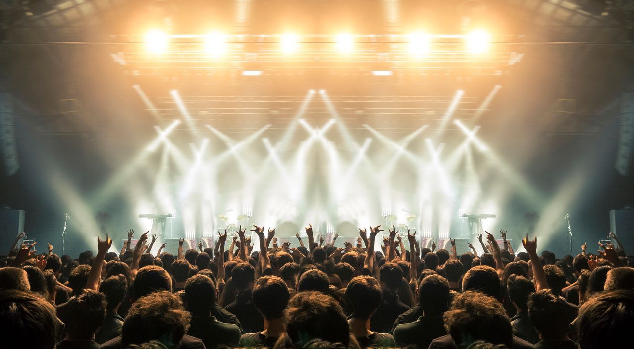 A crowd of people are standing in front of a stage at a concert.