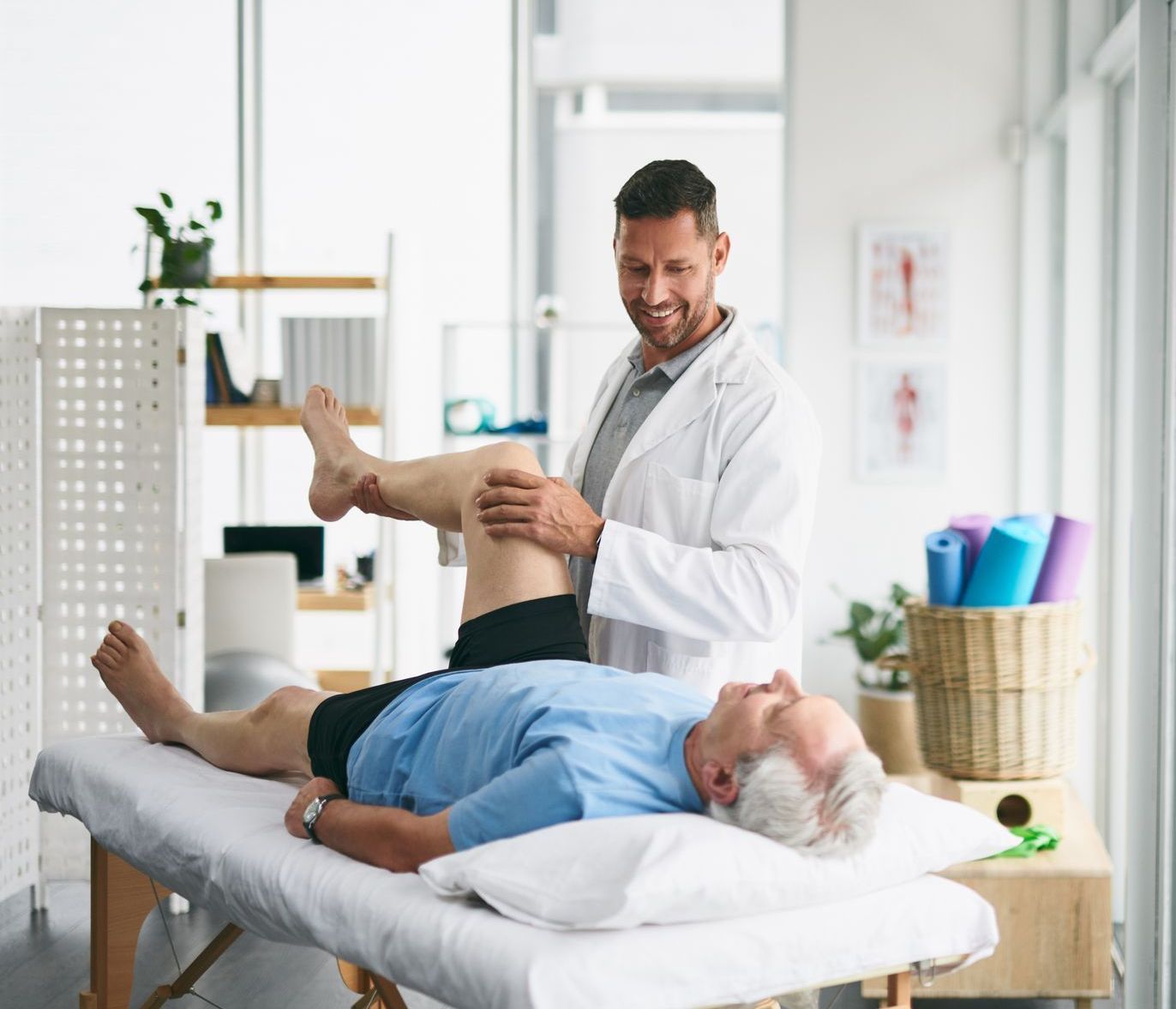 A man is laying on a bed while a doctor examines his leg.
