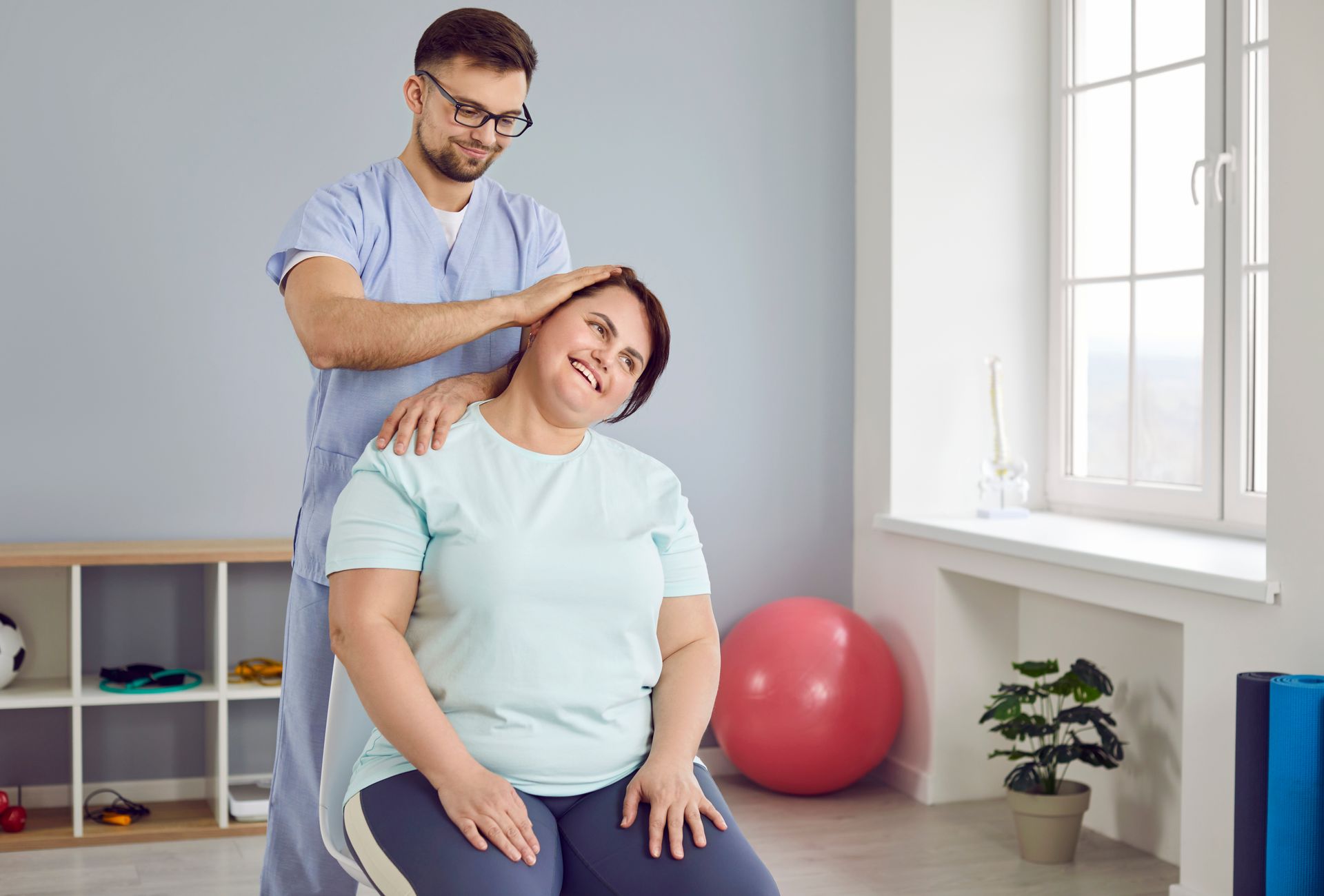 A man is stretching a woman 's neck in a gym.
