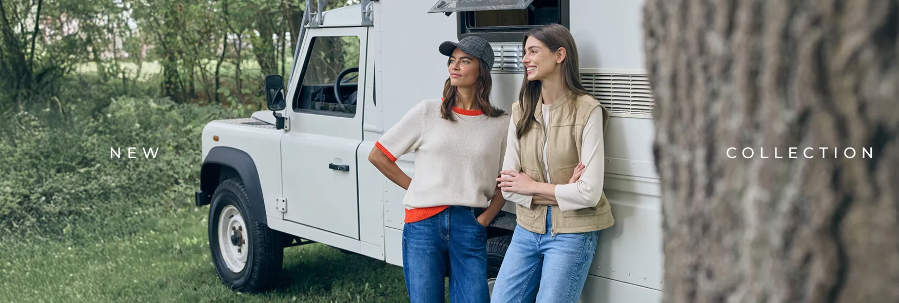 Due donne accanto a un camper e a un veicolo bianchi. Una indossa un berretto e l'altra sorride.