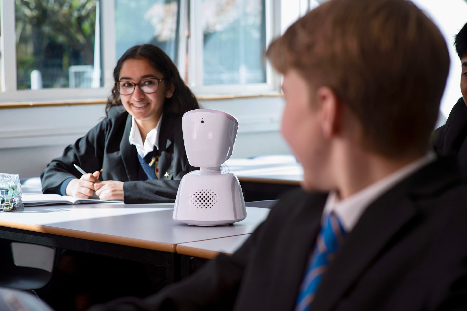 Un garçon et une fille sont assis à une table avec un robot devant eux
