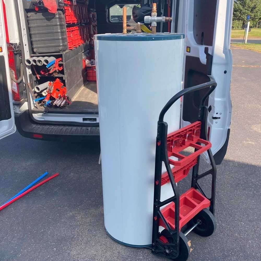 a water heater is sitting on a cart in front of a van .