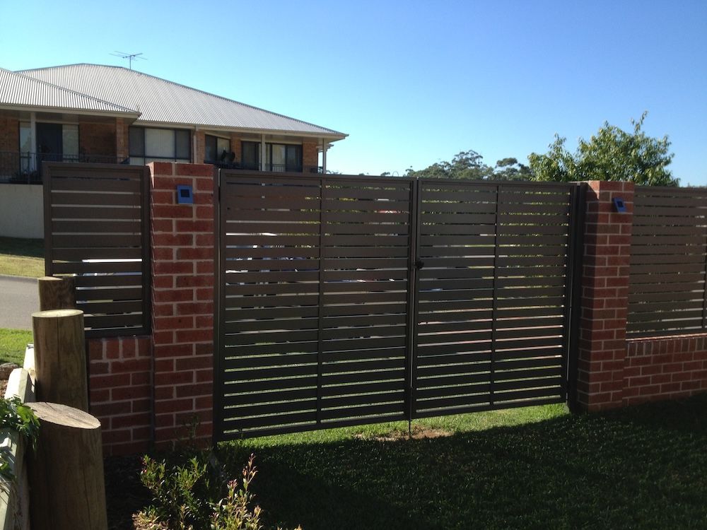 A Brick Wall and Black Metal Fence — Newcastle & MidCoast Privacy Screens & Gates In Kurri Kurri, NSW