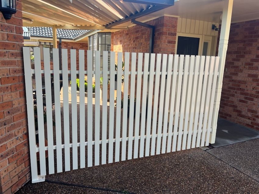 A White Picket Fence next to a Brick House — Newcastle & MidCoast Privacy Screens & Gates In Mid North Coast, NSW