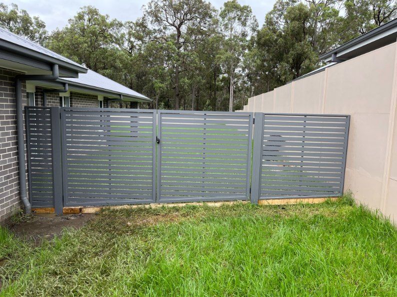 A Fence With a Gate in the Backyard of a House — Newcastle & MidCoast Privacy Screens & Gates In Kurri Kurri, NSW