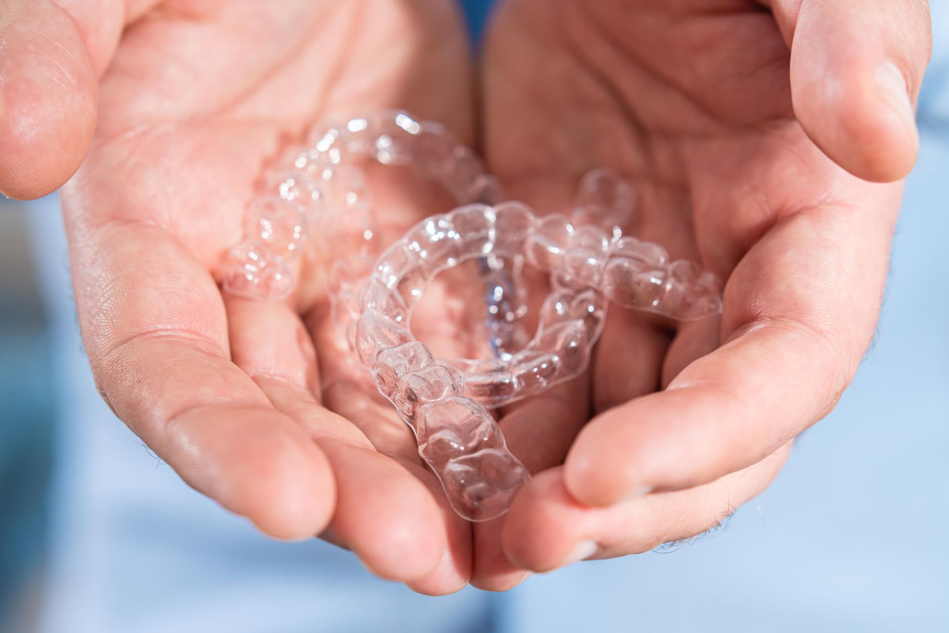 A person is holding a pair of clear braces in their hands.