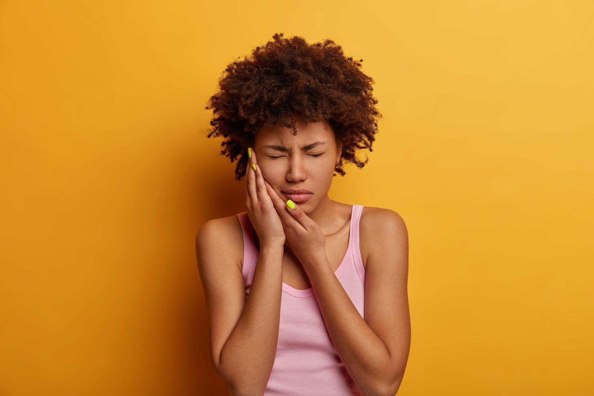 A woman is holding her face in pain because of a toothache.