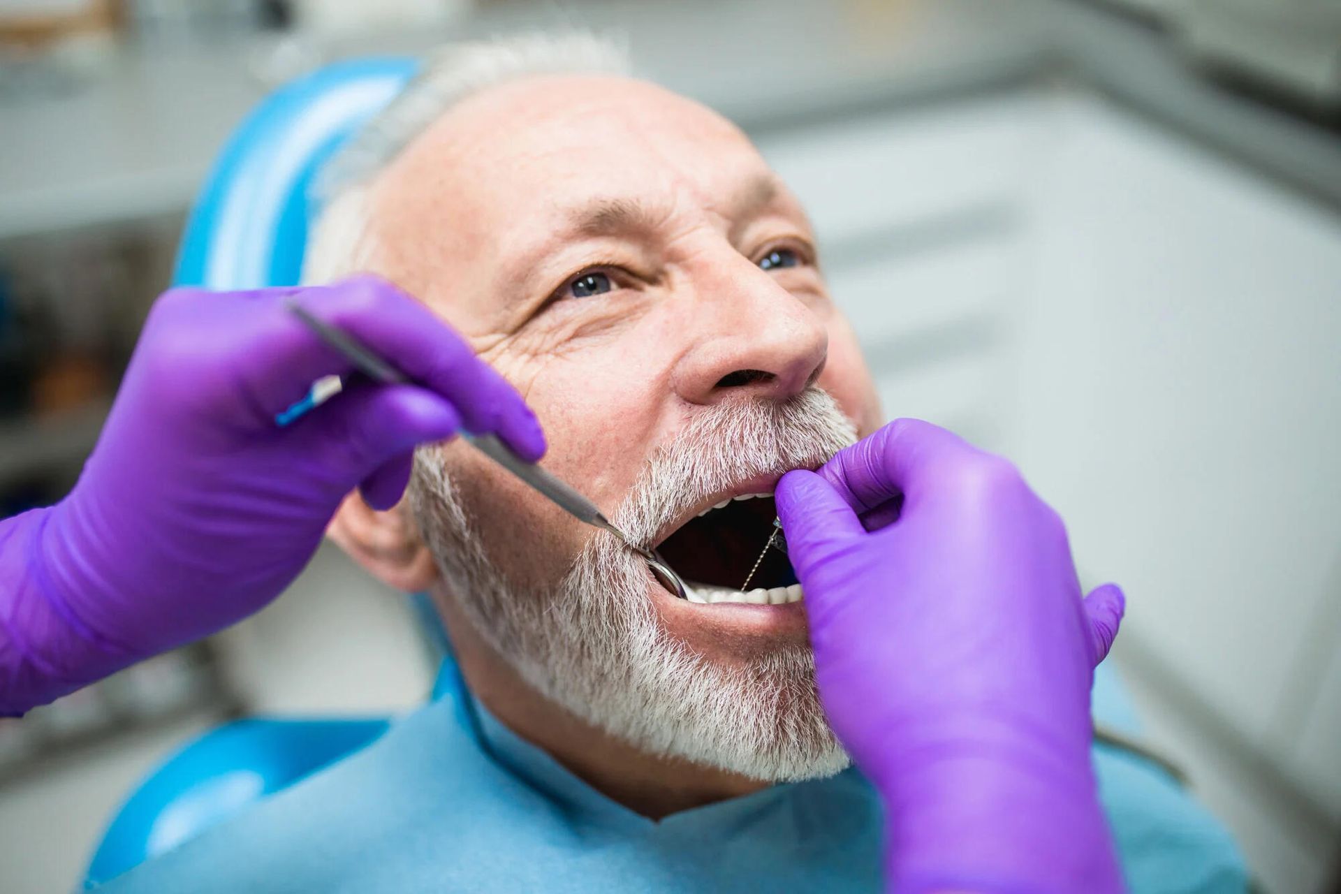 an older man is getting his teeth examined by a dentist .