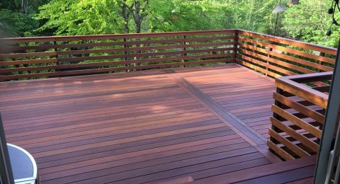 A wooden deck with a fence and trees in the background