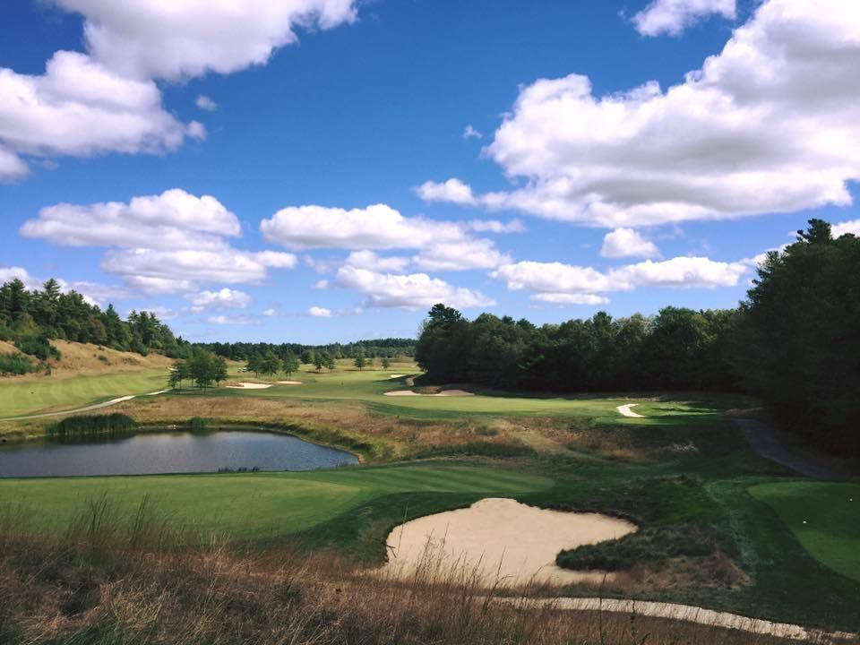 A golf course with a blue sky and white clouds