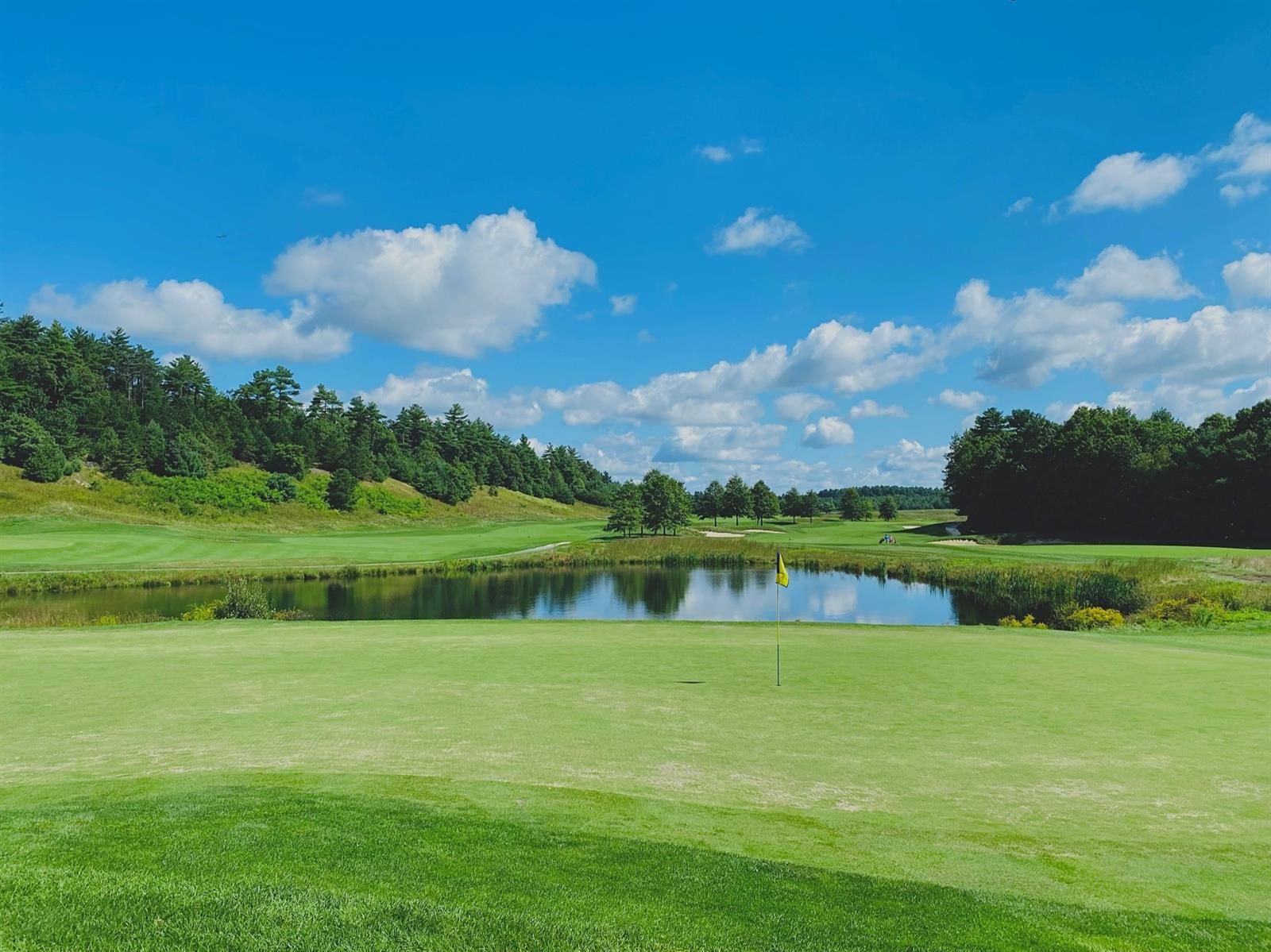 A golf course with a pond in the middle of it.