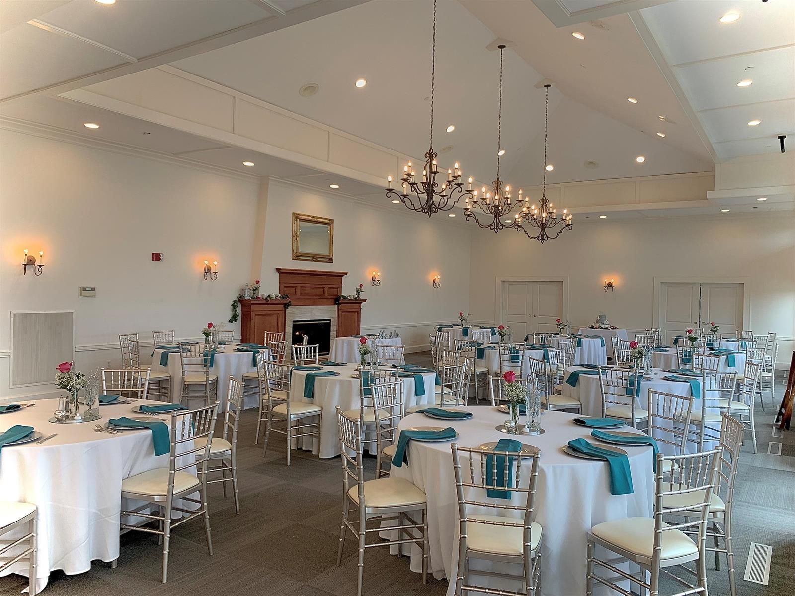 A large room with tables and chairs set up for a wedding reception.