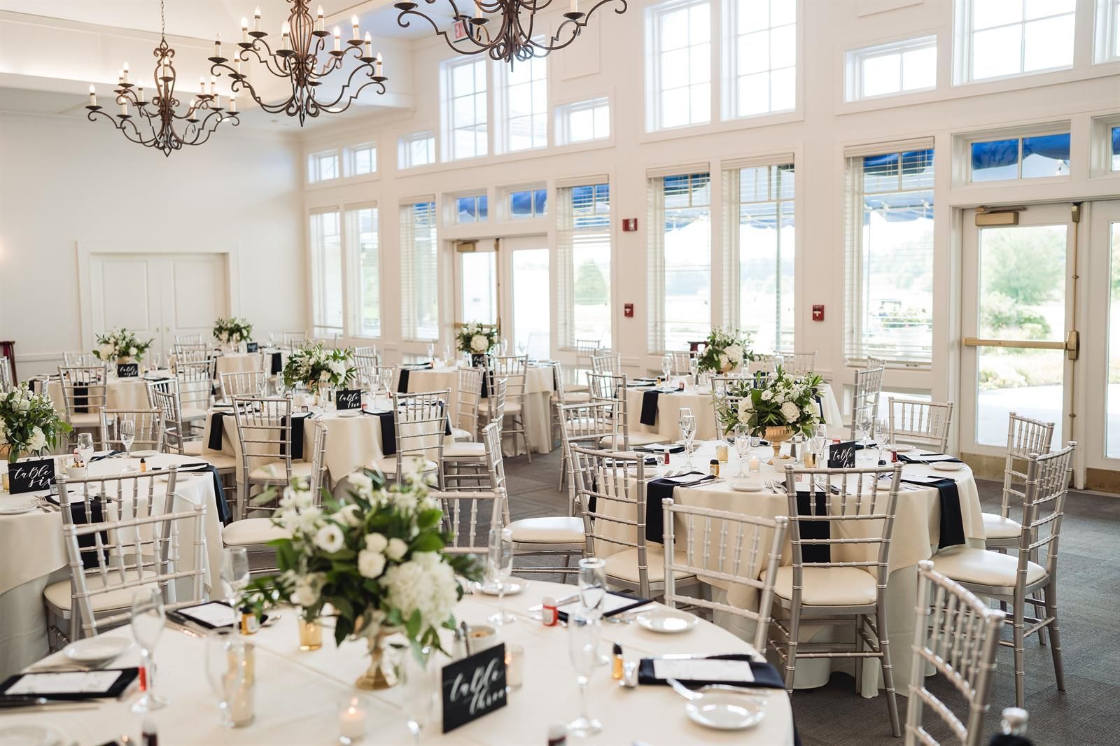 A large room with tables and chairs set up for a wedding reception.