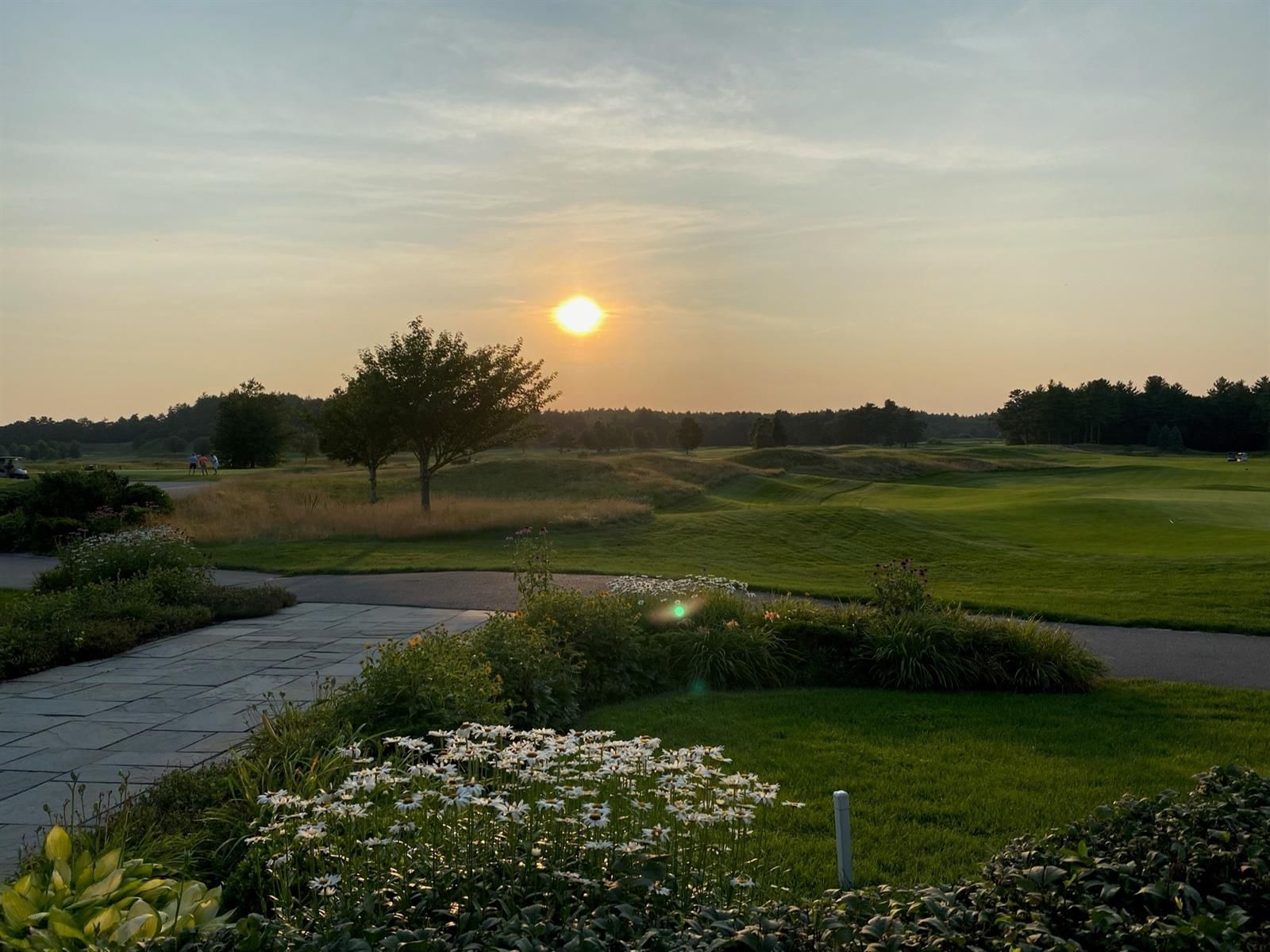 The sun is setting over a golf course at sunset.