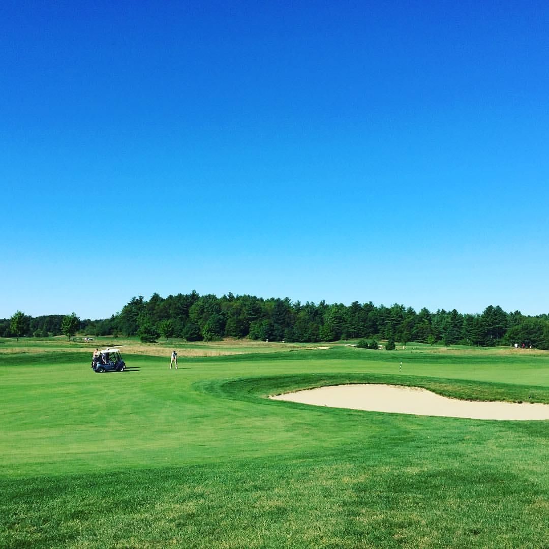 A golf cart is parked on the green of a golf course.