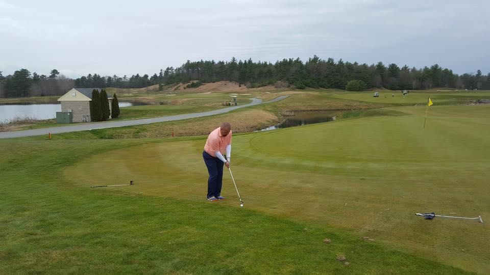 A woman is swinging a golf club on a golf course.