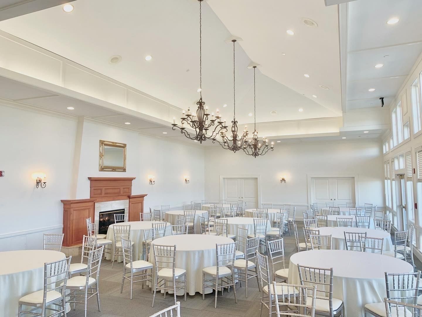 A large room with tables and chairs set up for a wedding reception.