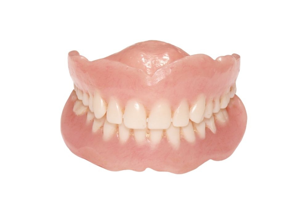 Dentures, top and bottom sets, with artificial pink gums and white teeth, isolated on white.