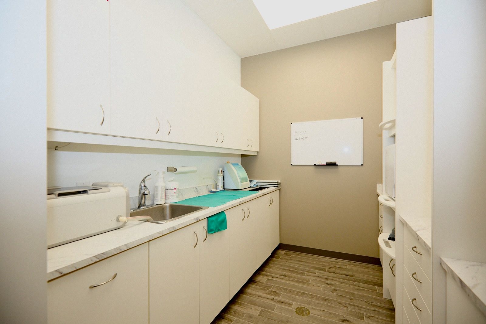 Dental office sterilization room with white cabinets, sink, and medical equipment.