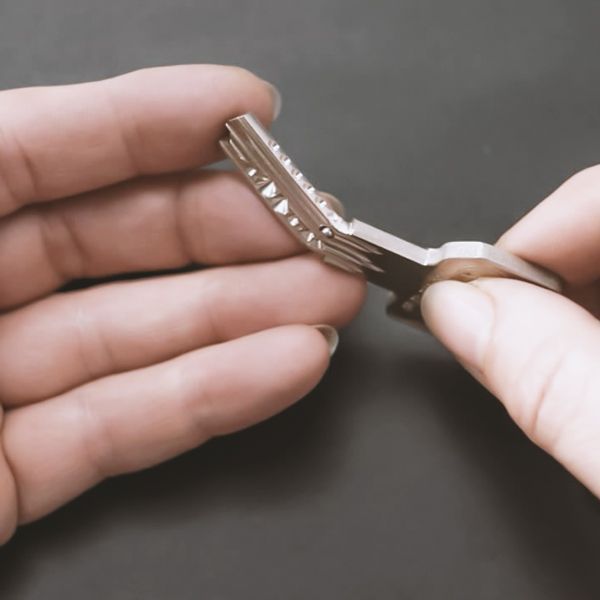 A Woman Holds A bent Car Key In Her Fingers.